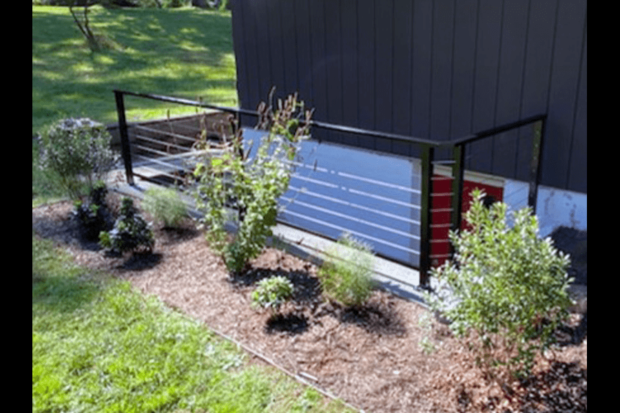 Black metal cable railing on outdoor staircase leading to a red door