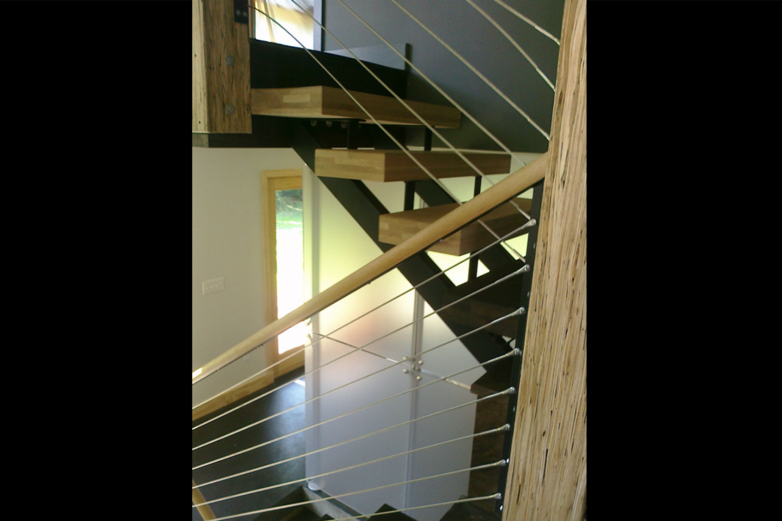 Grey metal cable railing on wooden indoor staircase