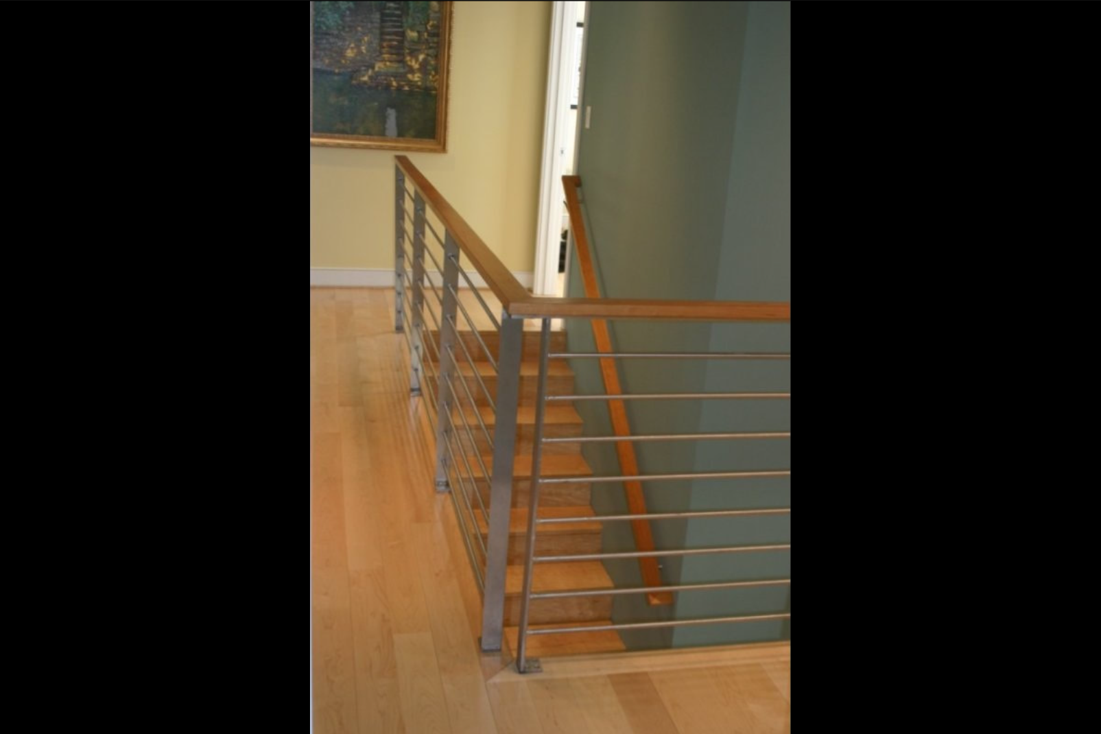 Photo of grey metal cable railing on wooden indoor staircase from the top