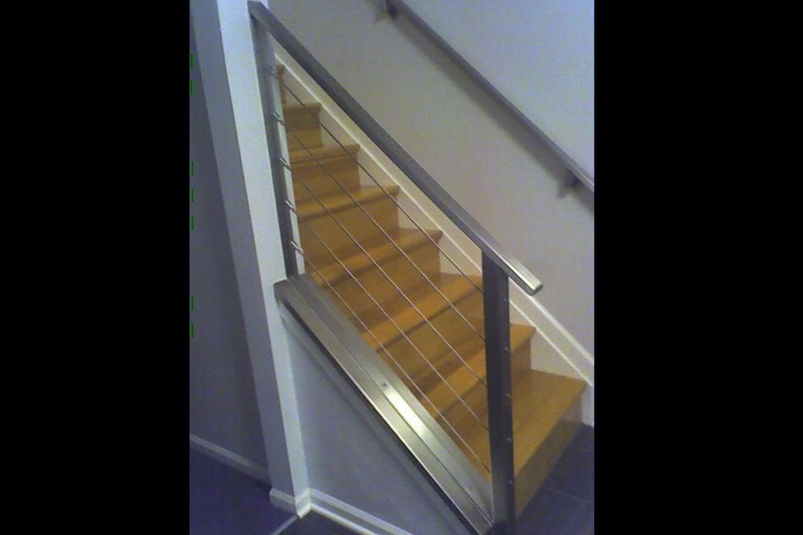 Photo of grey metal cable railing on wooden indoor staircase from the bottom