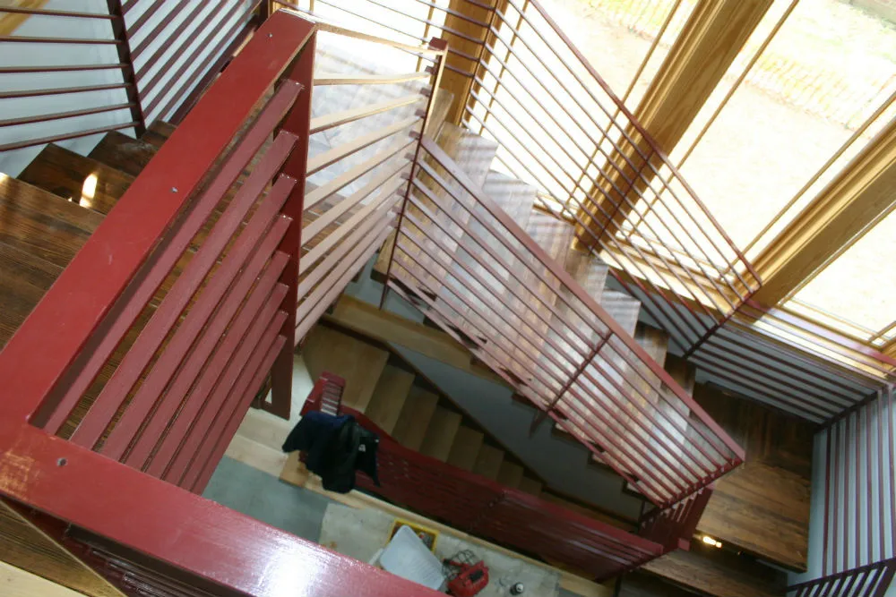 Photo of red welded metal commercial railing on wooden indoor staircase