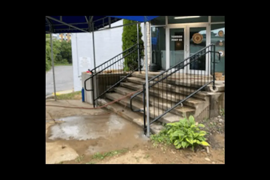 Photo of black commercial railing for an outdoor staircase with a blue tent over it leading up to glass doors