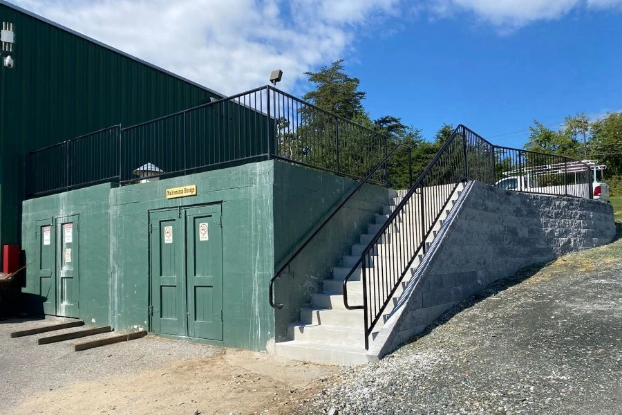 Photo of black metal commercial railing for outdoor staircase next to green doors
