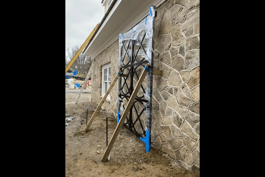 Photo of black decorative metalwork being installed along the side of a house