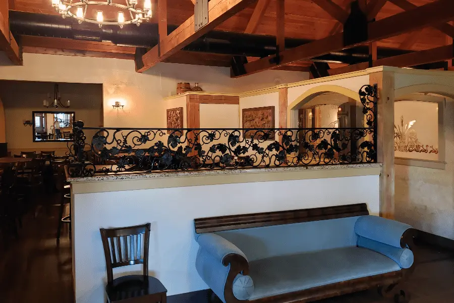 Photo of black decorative metalwork designed to look like leaves and vines installed on top of a half wall in a restaurant
