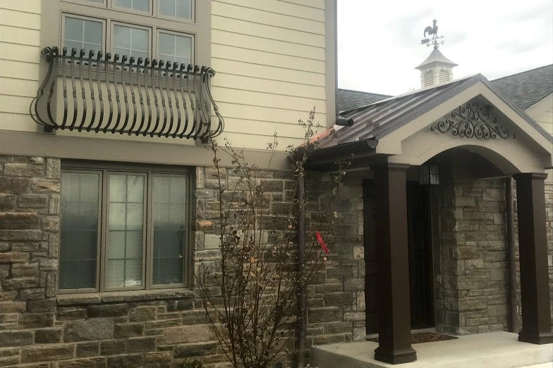 Photo of black metal decoration in an archway above a front door and curved black metal faux balcony