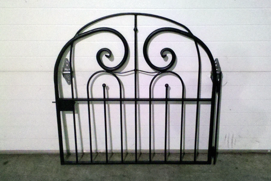 Photo of small black gate for a pathway sitting against a white wall