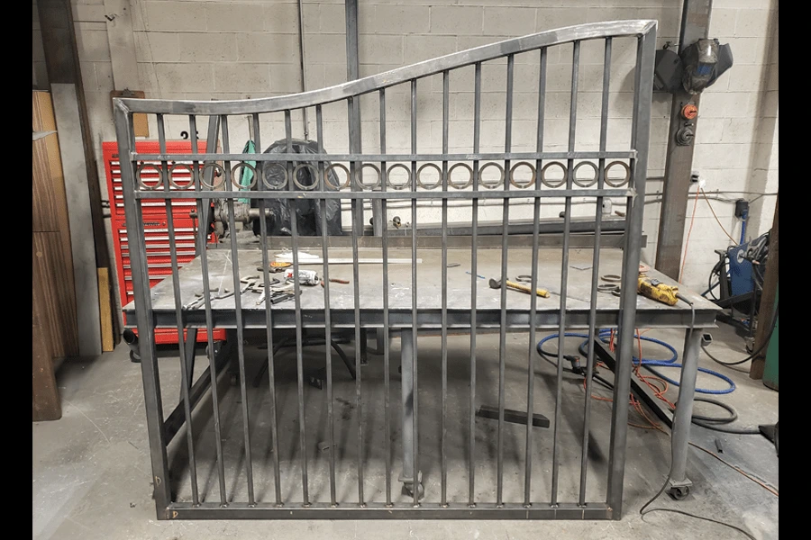 Photo of half of a welded metal gate for a road with decorative metalwork in a workshop