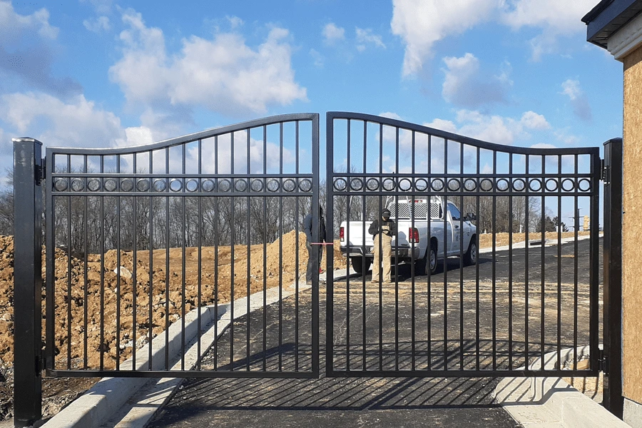Photo of black metal gate with decorative metalwork in place over a road
