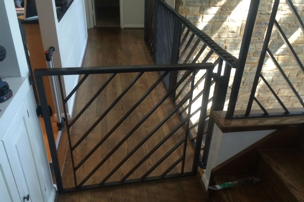 Photo of a black metal gate next to black metal guardrails in an indoor setting 