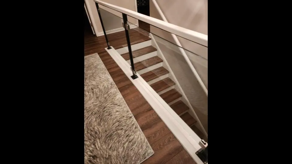 Photo of residential glass railing on indoor staircase with black and white metal rails