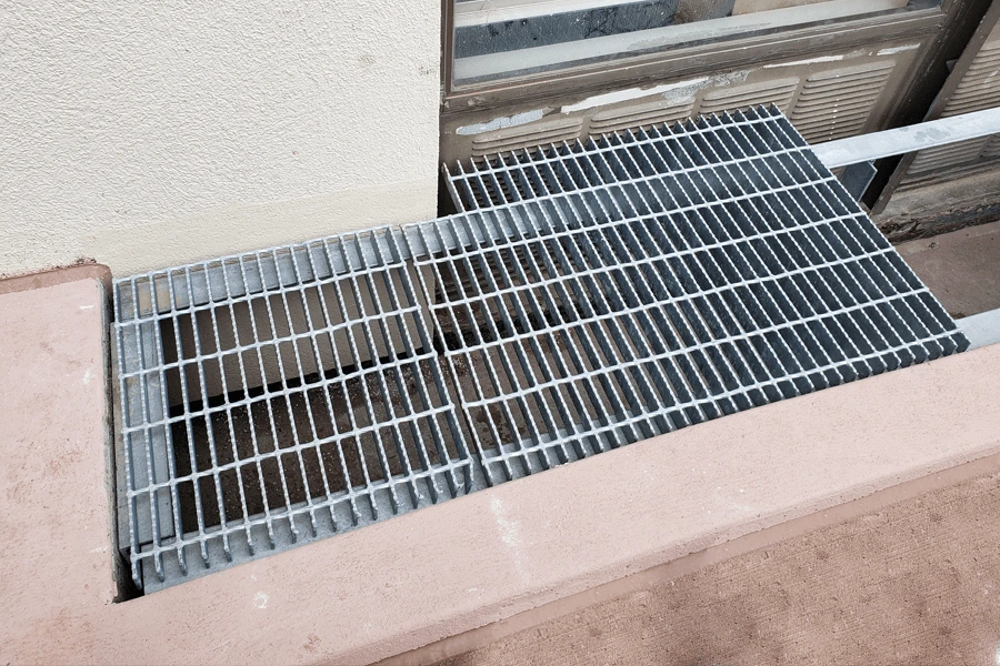 Photo of gray custom metal grating attached to tan concrete