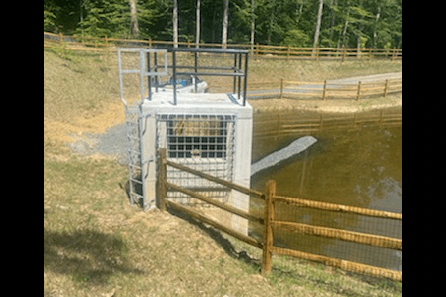 Photo of grey custom metal grating as a window on a concrete structure by a pond
