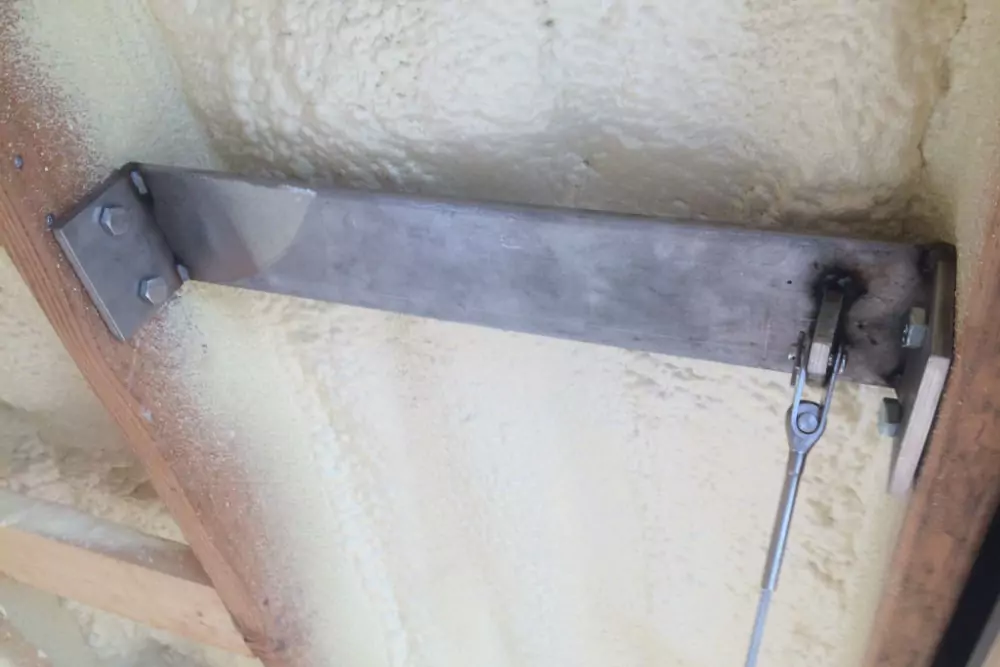Photo of grey-brown metal bar with grey metal cord attachment