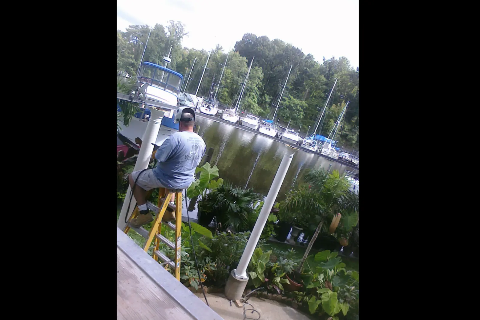 Photo of man working on an in-progress white metal pavillion at a marina