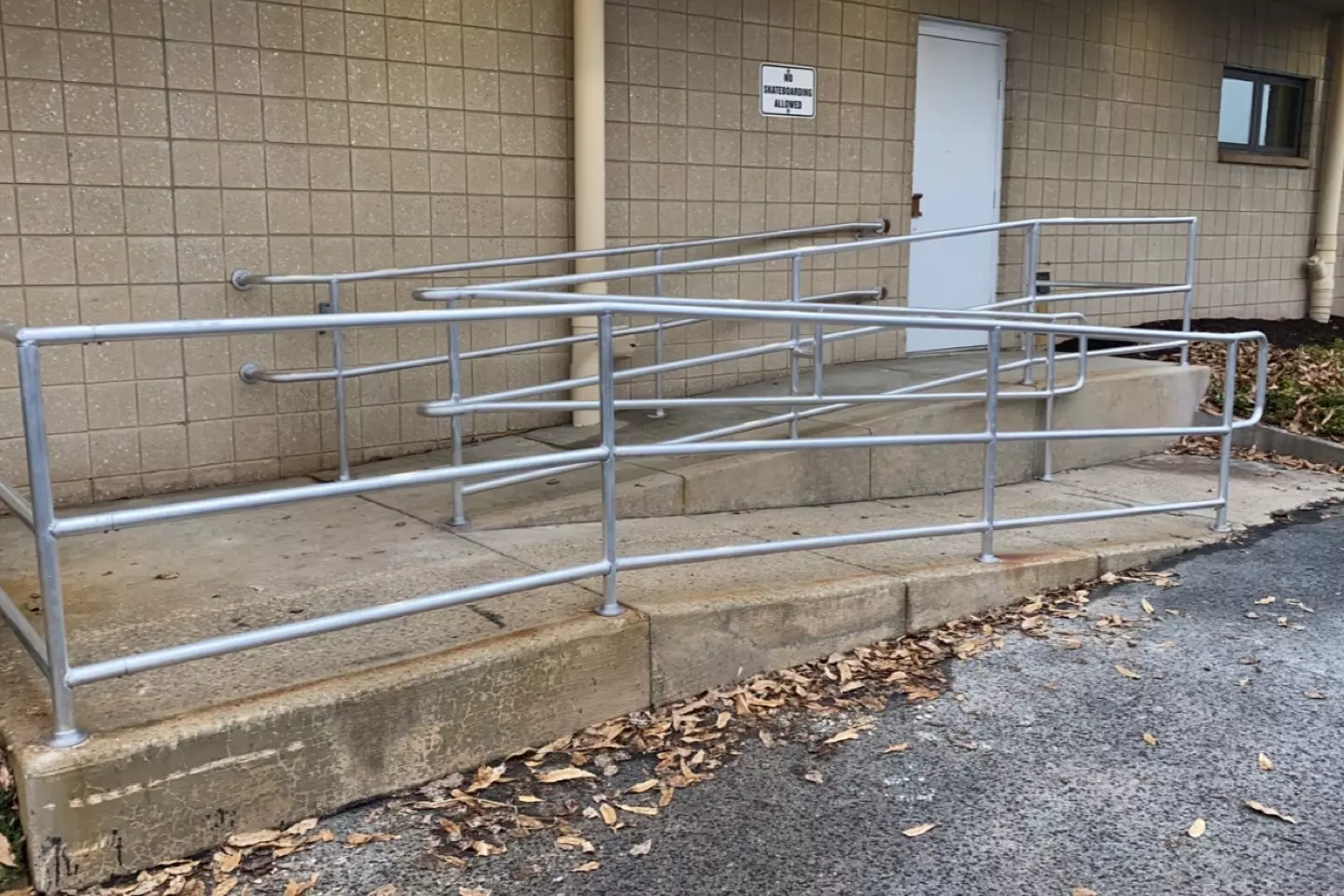 Photo of silver metal pipe railing on a ramp entrance to a building