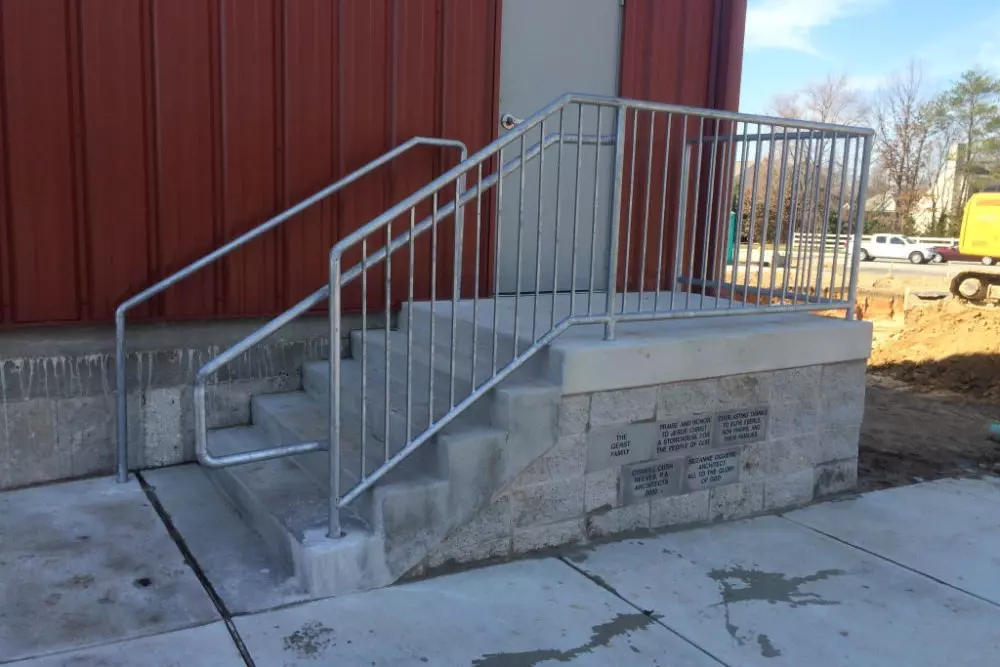 Photo of grey-silver metal pipe railing outside a red building
