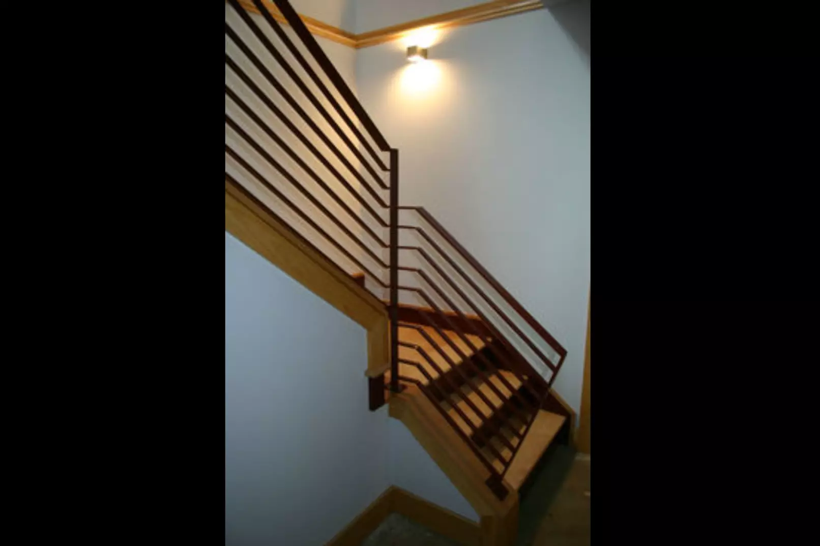 Photo of black reddish-brown metal railing on an indoor residential staircase