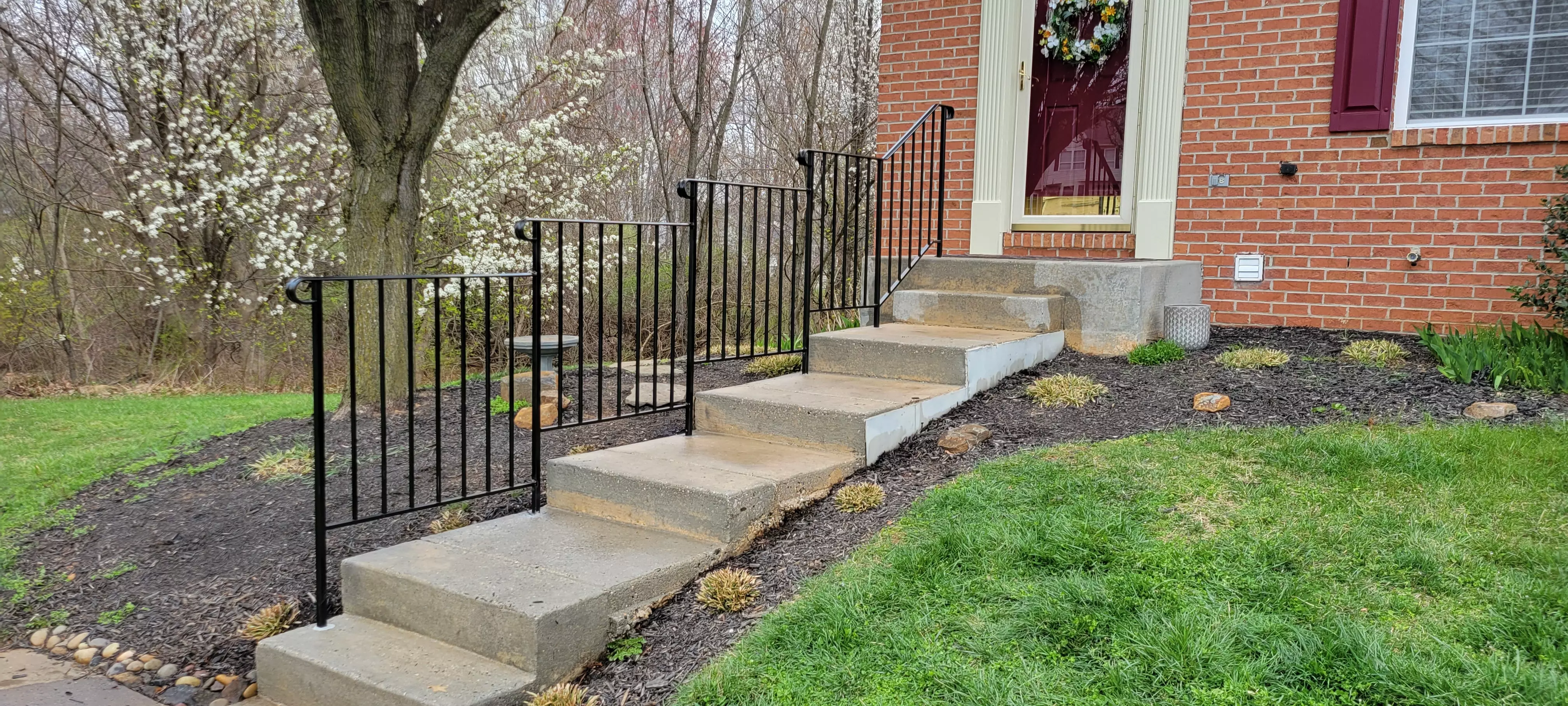 Photo of black metal residential railing on an oudoor staircase with curved edges