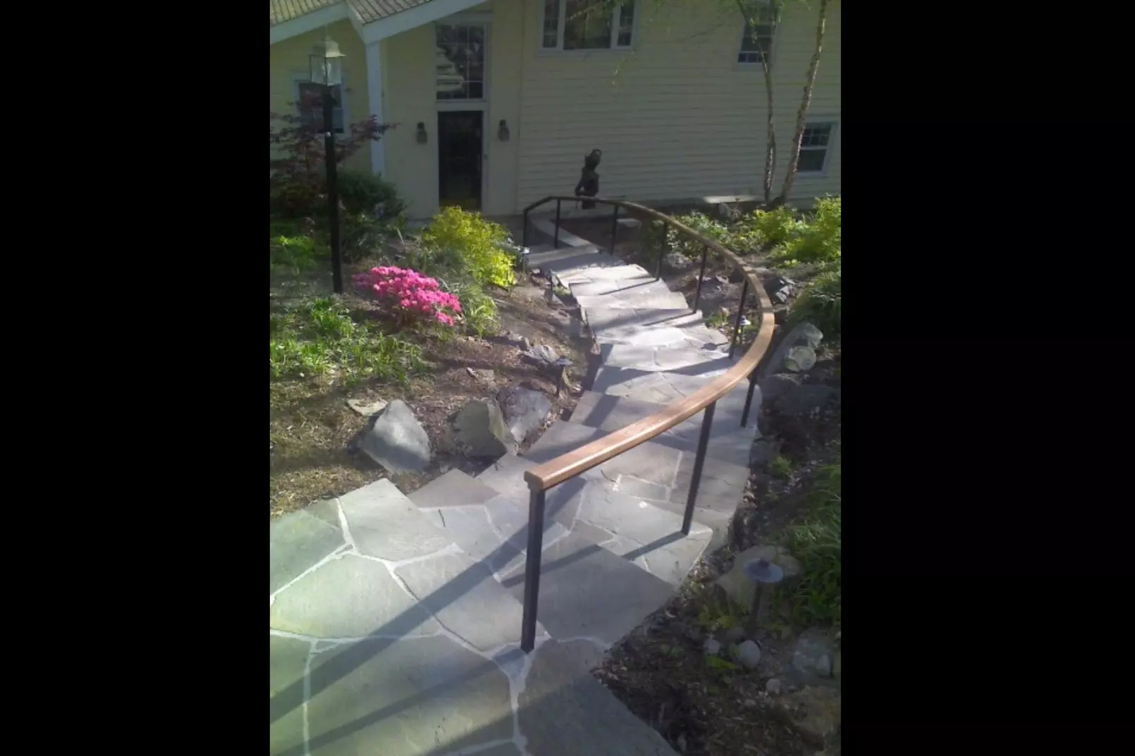 Photo of black metal railing with decorative wooden top on an outdoor staircase
