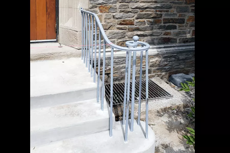 Photo of curved grey metal railing on outdoor steps 