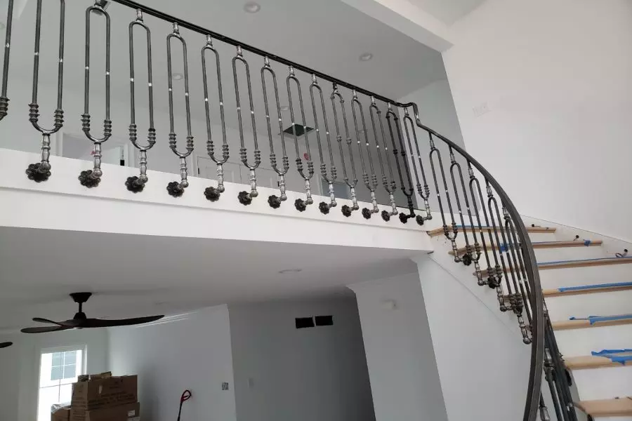 Photo of specially designed black metal railing with intricate detail focused on curved staircase 