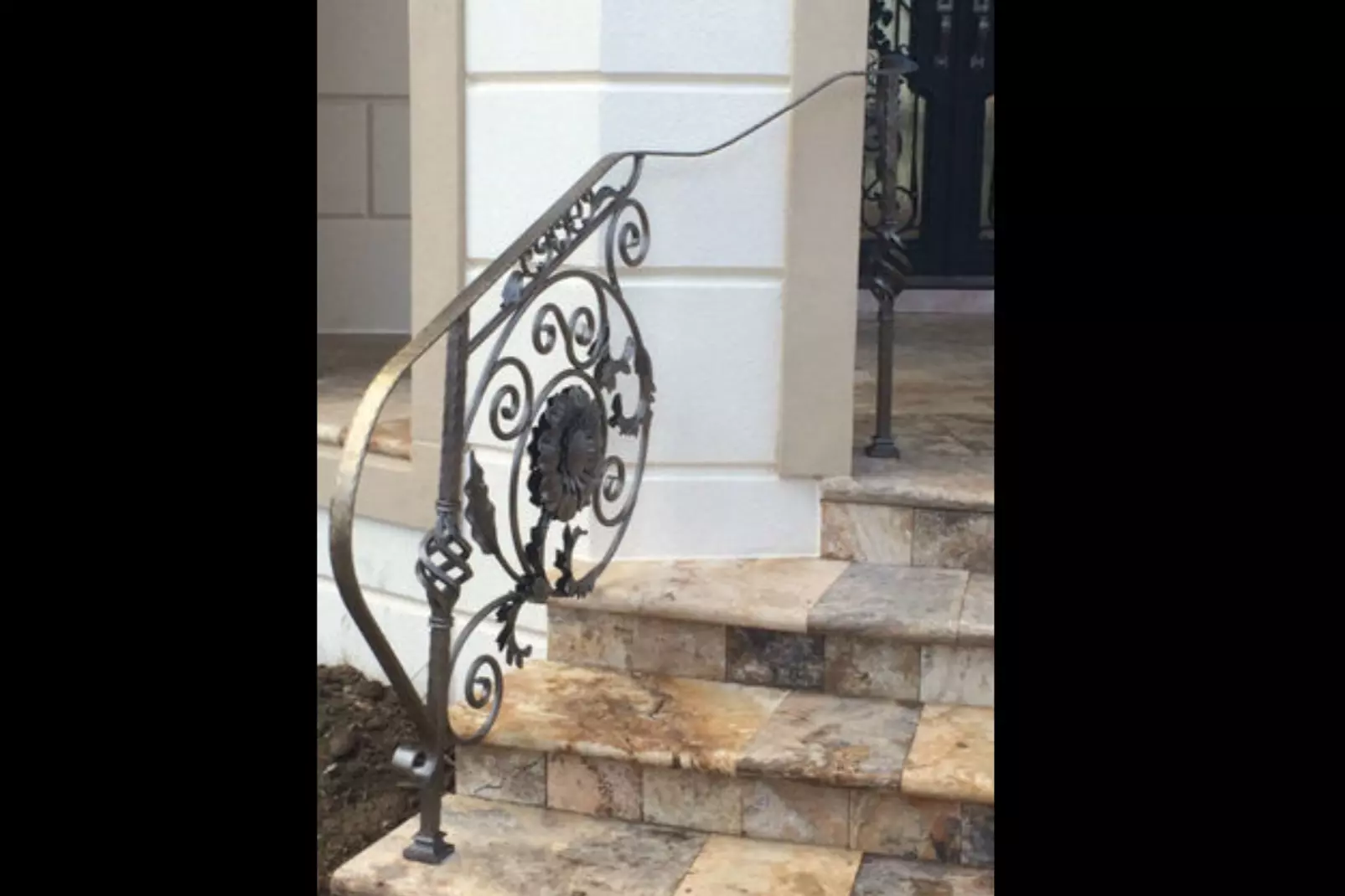 Photo of grey metal floral welded design railing on an outdoor staircase