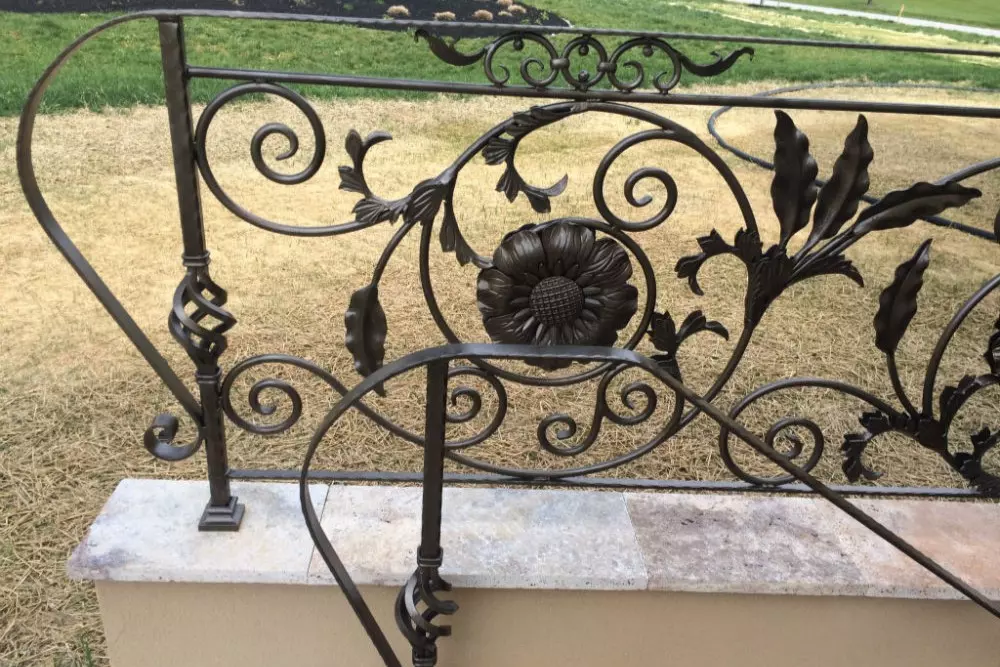 Zoomed-in photo of details on grey metal floral railing design