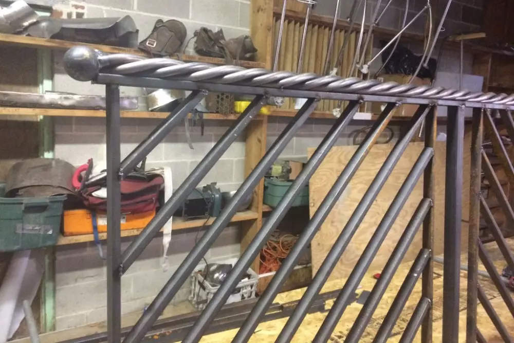 Photo of grey metal railing with twisted metal strand design in warehouse