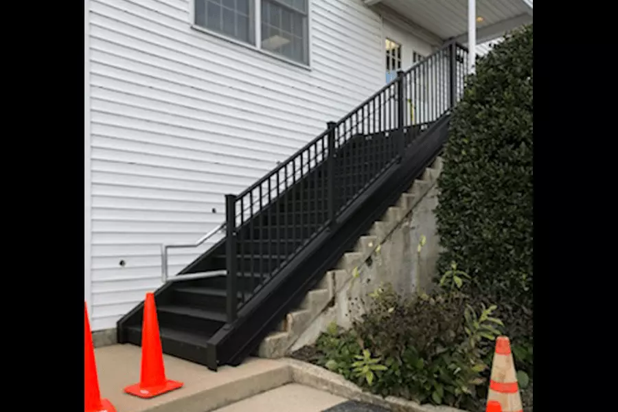 Photo of black metal outdoor stairs with silver railing leading up to a white building