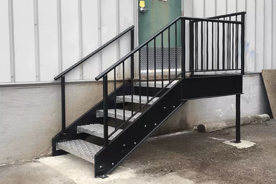 Photo of a black metal iutdoor staircase leading up to a green door